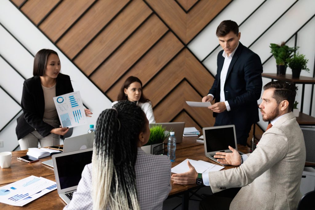 business meeting of businessmen at a large desktop with laptops